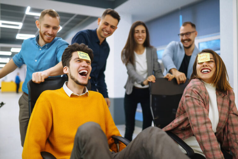 Importancia de la inteligencia espiritual - Equipo de oficina divirtiéndose con juegos y carreras en sillas giratorias.