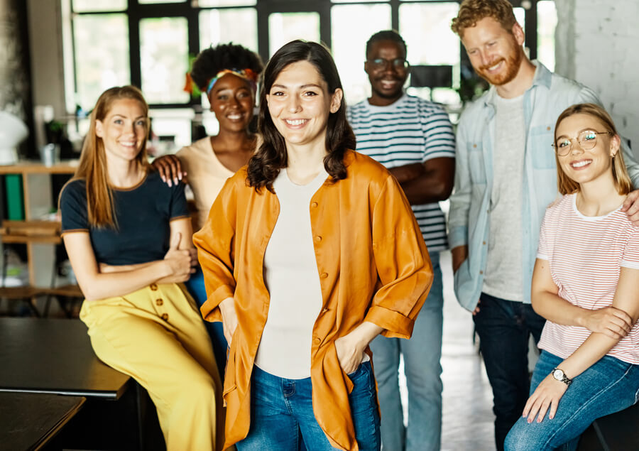 Tecnología y talento humano comunicación - Equipo diverso de trabajo posando juntos y sonriendo en oficina creativa.
