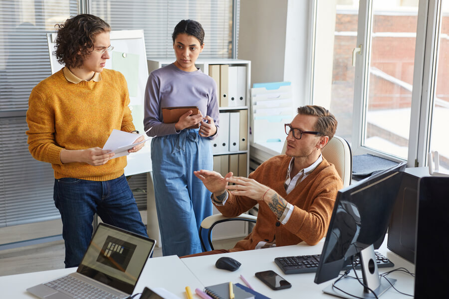 Tecnología y talento humano importancia - Equipo de oficina en reunión analizando ideas frente al computador.
