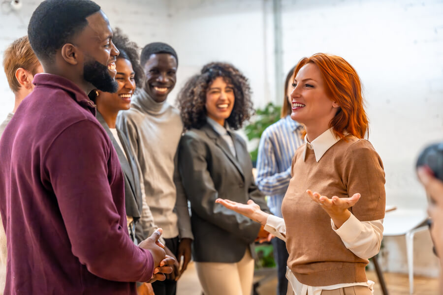 Proceso de reclutamiento y selección introduccion - Grupo de personas en una oficina interactuando y sonriendo durante una dinámica de integración o networking.