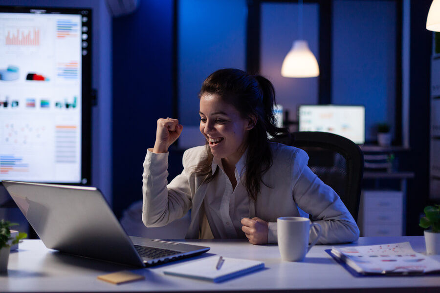 Sistemas de pagos de nómina en Colombia como elegir - Mujer de negocios celebrando un logro frente a su laptop en la oficina.