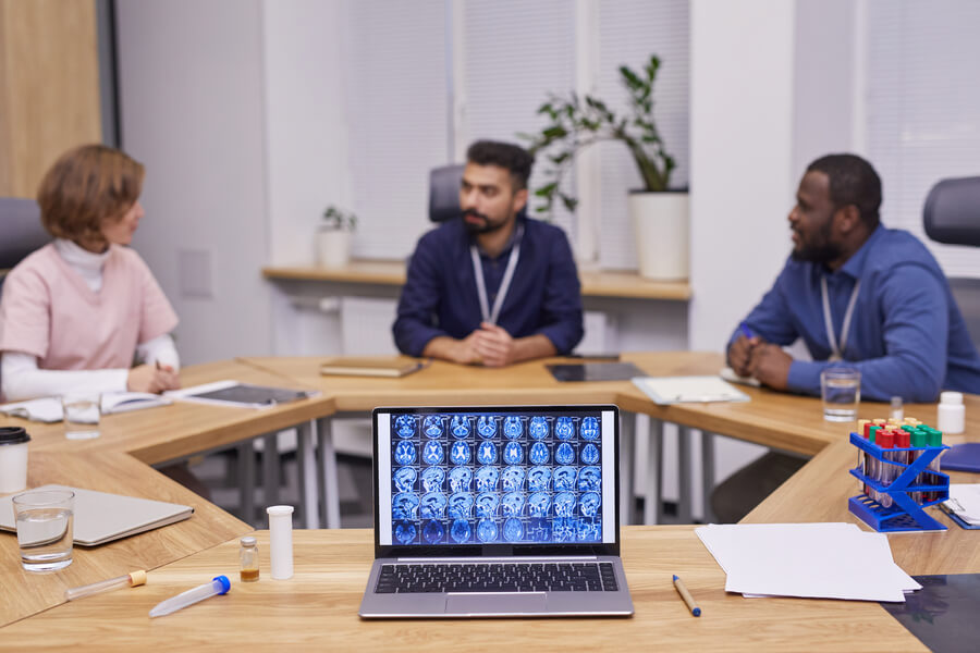 Beneficios de la inteligencia artificial para las empresas introduccion - Reunión de médicos analizando imágenes de resonancia en una computadora portátil.