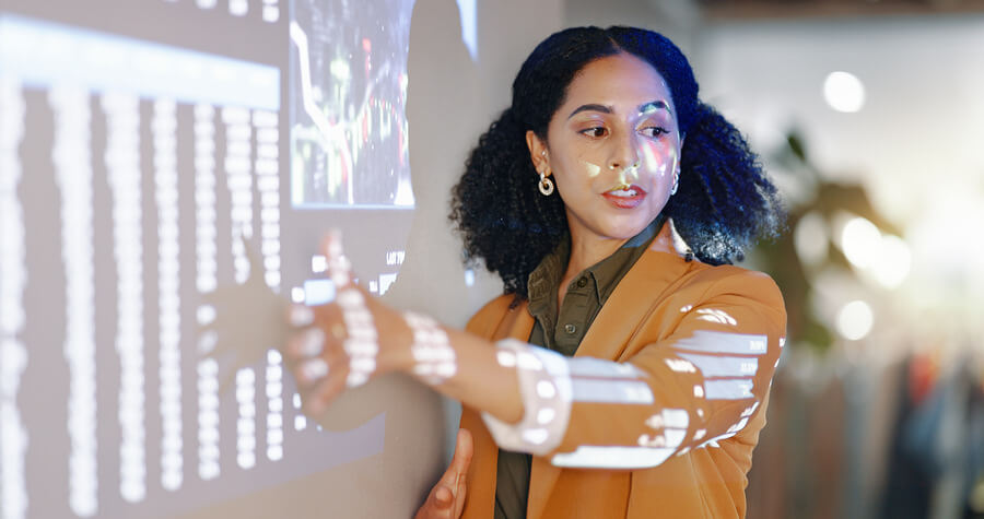 Beneficios de la inteligencia artificial para las empresas personalizacion - Mujer presentando datos proyectados en una pantalla durante una exposición.