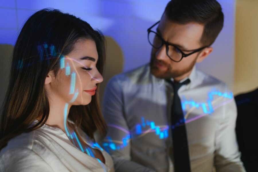 Beneficios de la inteligencia artificial para las empresas - Dos colegas analizando gráficos financieros proyectados en la oficina.