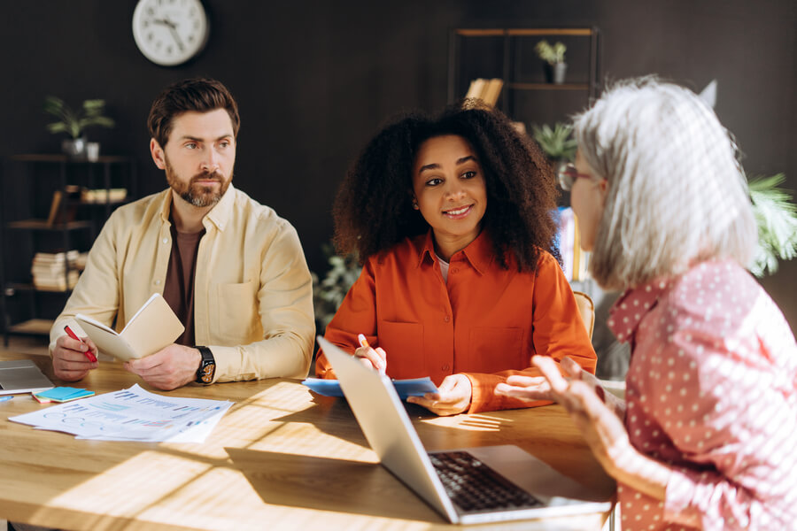 Payrolling que es herramientas - Tres personas en reunión de trabajo conversando sobre informes.