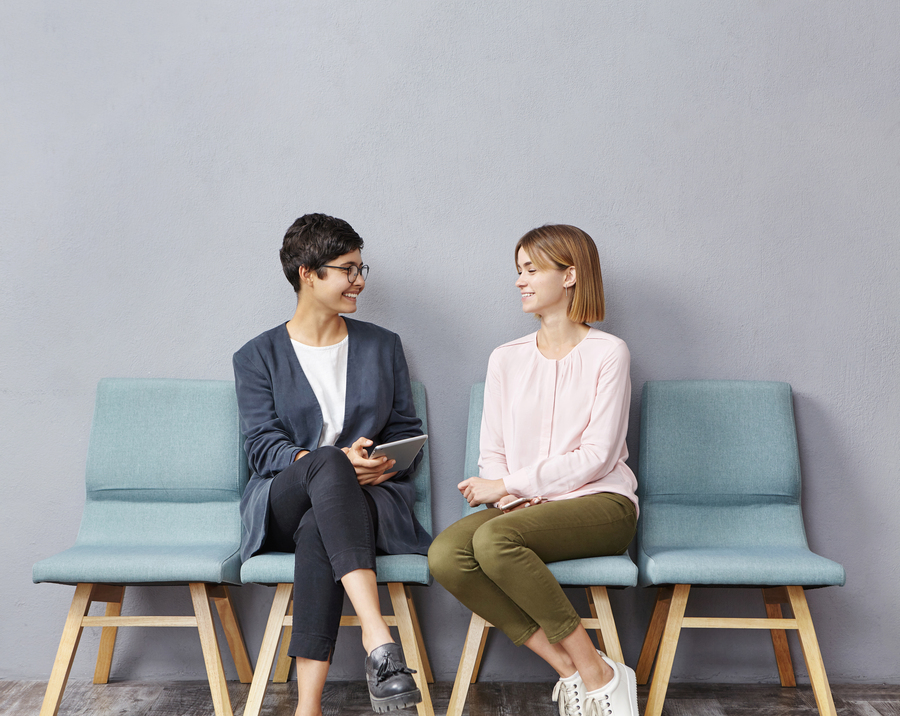 Técnicas de selección de personal - Dos mujeres conversando sentadas en una sala de espera.