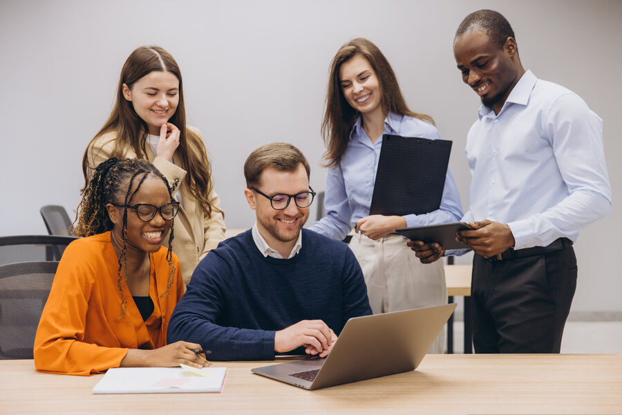 10 pasos para un proceso de selección efectivo - Equipo de trabajo sonriendo mientras revisa información en una computadora portátil.