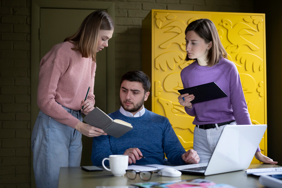 Ley 2121 de 2021 errores comunes - Equipo de trabajo colaborando en oficina con documentos y laptop.