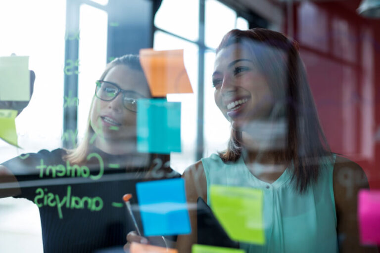 Software de nóminas más utilizados en colombia - Dos personas trabajando con notas adhesivas en una sesión de ideas.