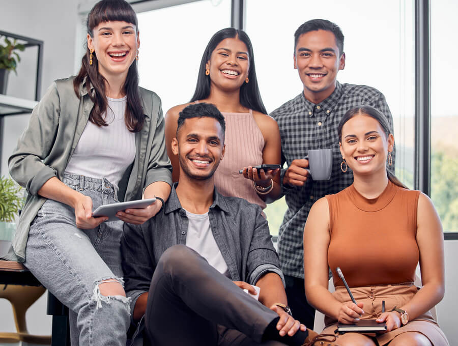 Grupo de jóvenes profesionales sonriendo durante una reunión en la oficina.
