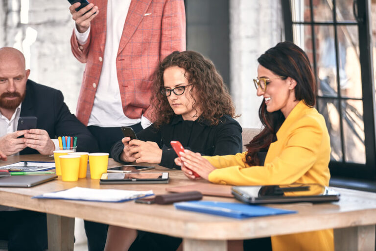 Como liquidar una nómina - Personas usando el celular durante una reunión.