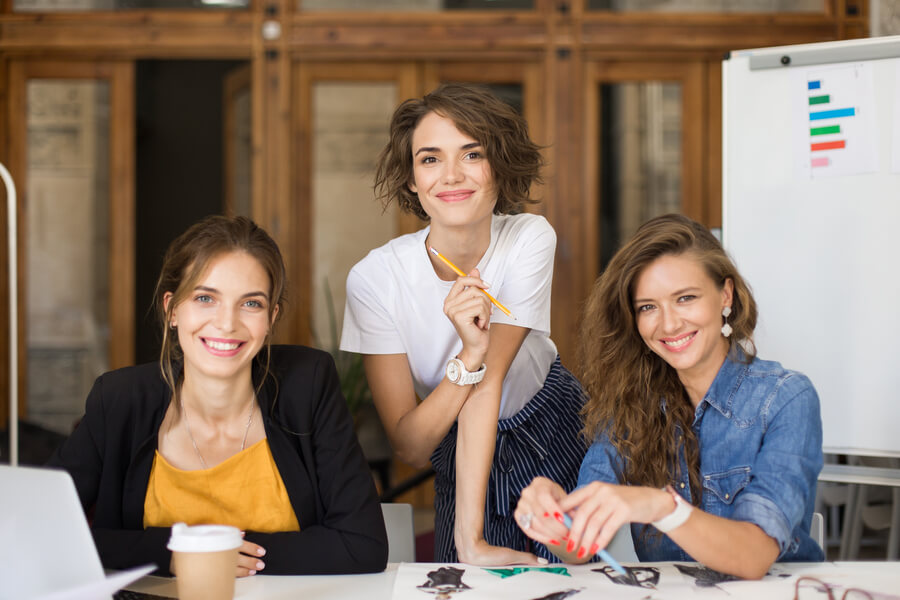 Gestión de nómina casos de éxito - Tres mujeres sonrientes trabajando en un proyecto creativo.