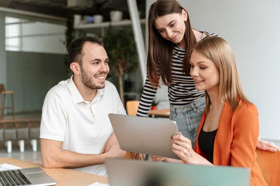 Gestión de nómina introducción - Tres colegas colaborando frente a una laptop con actitud positiva.