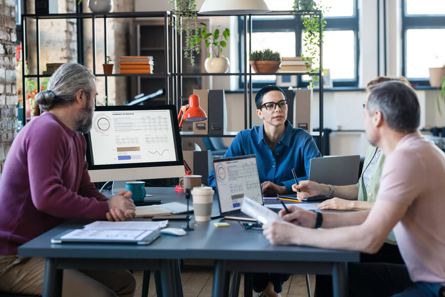 evaluar el desempeño de los empleados - Equipo de trabajo en reunión analizando gráficos en computadora.