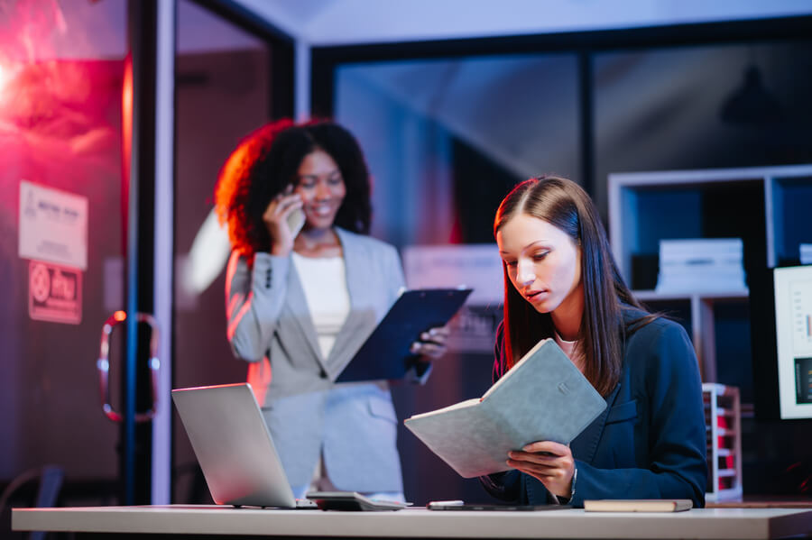 Ambiente laboral nocturno con profesionales concentradas en tareas.